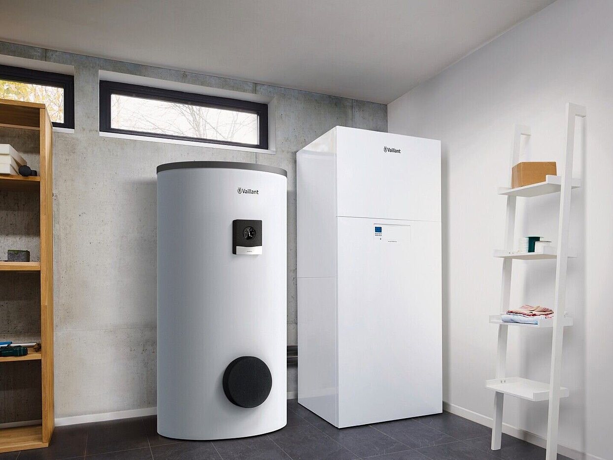 © Vaillant Innenaufstellung einer Wärmepumpe: In einem kellerarum mit Oberlichtern steht eine Vaillant Heizungswärmepumpe versoTHERM plus in der rechten Eceke, daneben ein Wärmespeicher. Außerdem sind noch zwei Regale zu sehen.