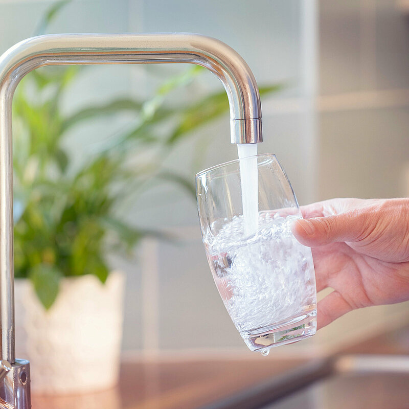 Glas wird am Wasserhahn gefüllt