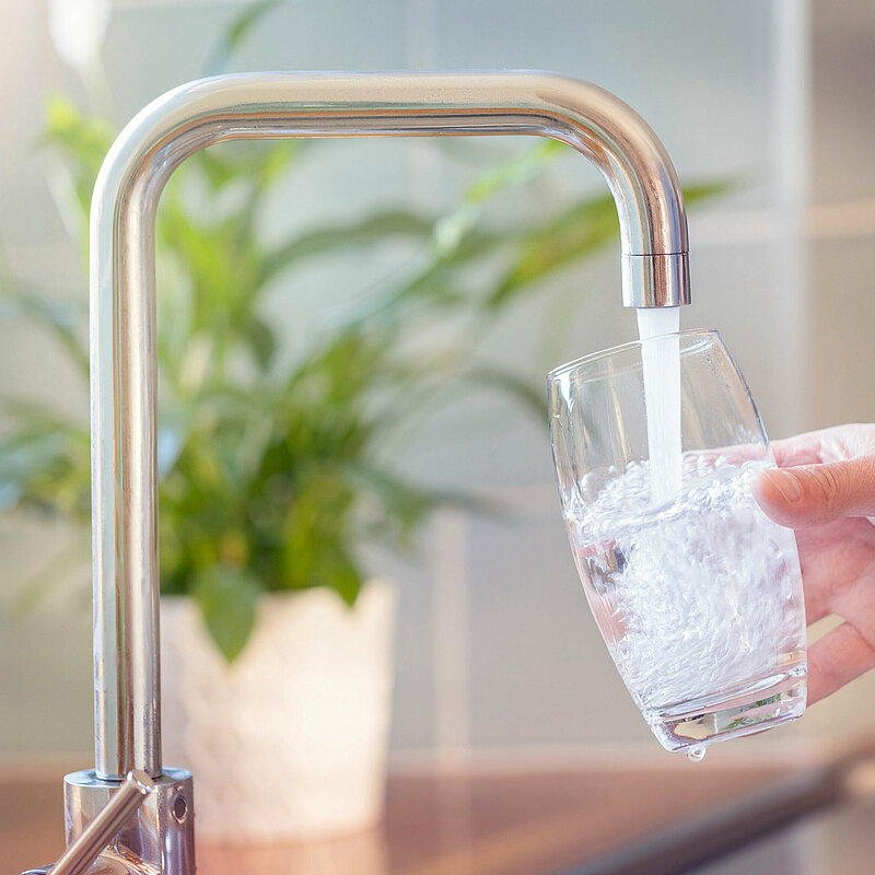 Glas wird am Wasserhahn gefüllt