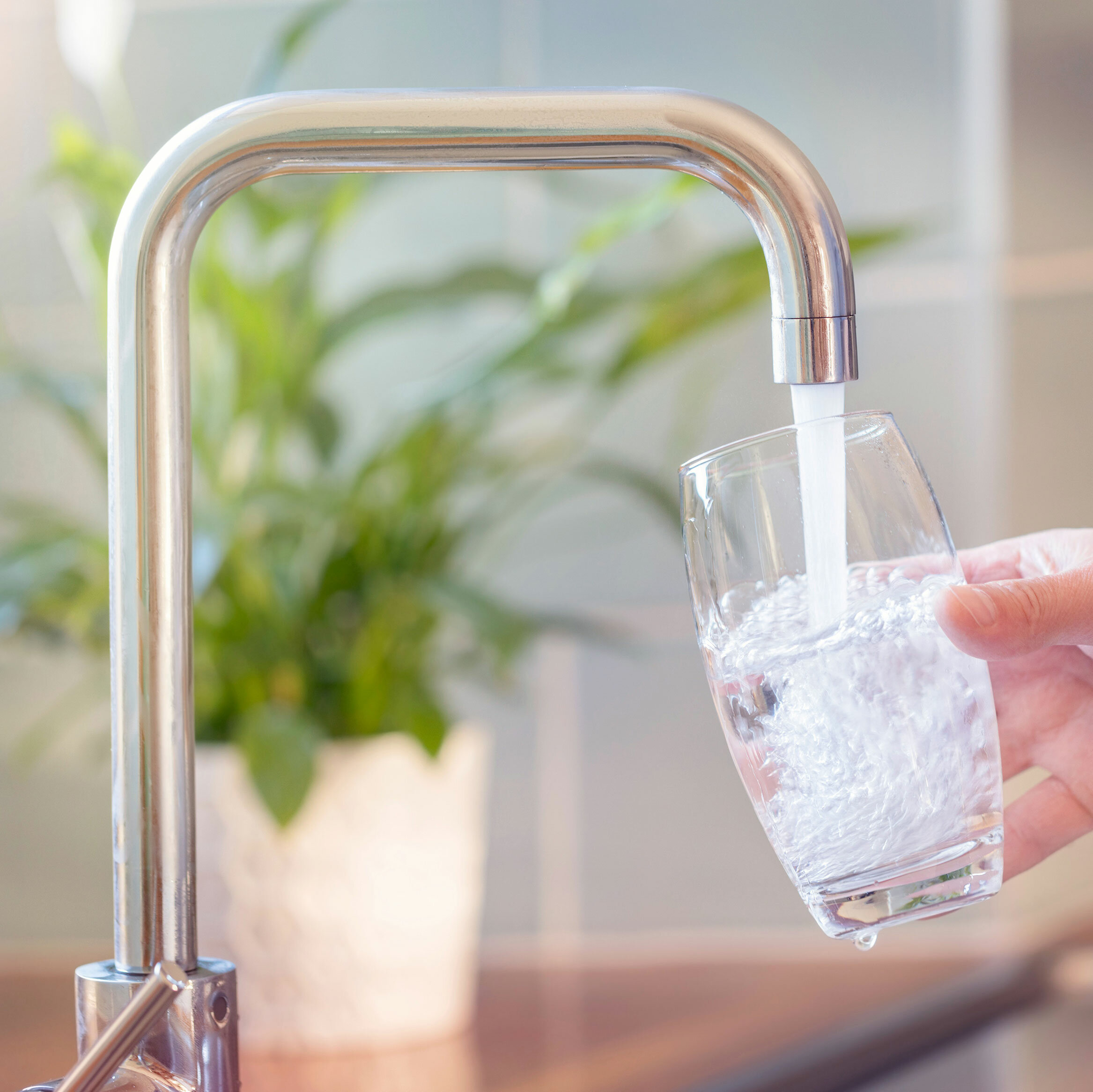 Glas wird am Wasserhahn gefüllt