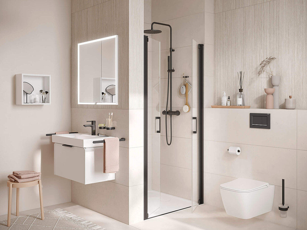 Kleines Bad mit Waschtisch und Lichtspiegel, Dusche und WC. Boden, Wände und Dekoartikel in Pastelltönen. Armaturen und Accessoires in schwarz.