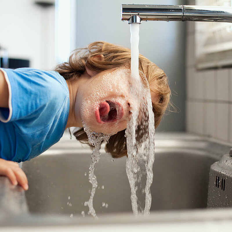 Kind trinkt aus Wasserhahn