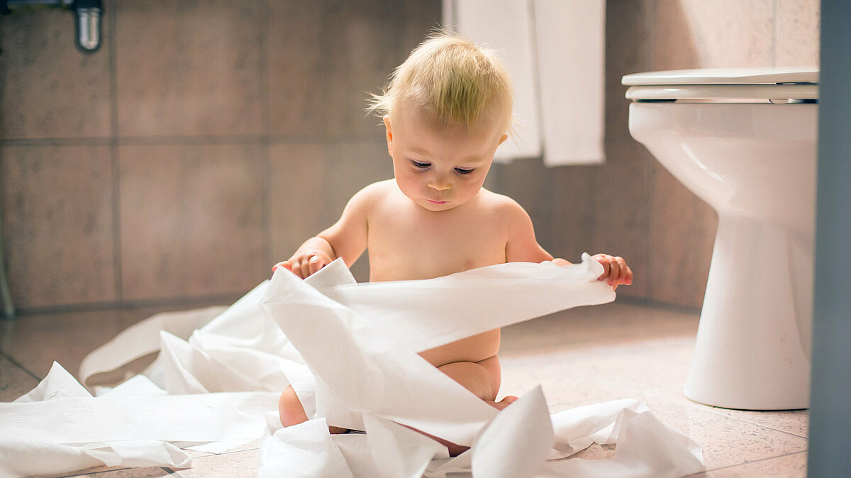 Kleinkind spielt mit Toilettenpapier